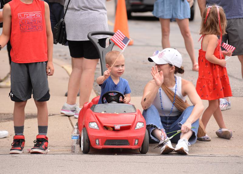 Oliver and Amy Stansbury of Downers Grove wave to firemen during the Downers Grove Fourth of July Parade on Thursday, July 4, 2024.