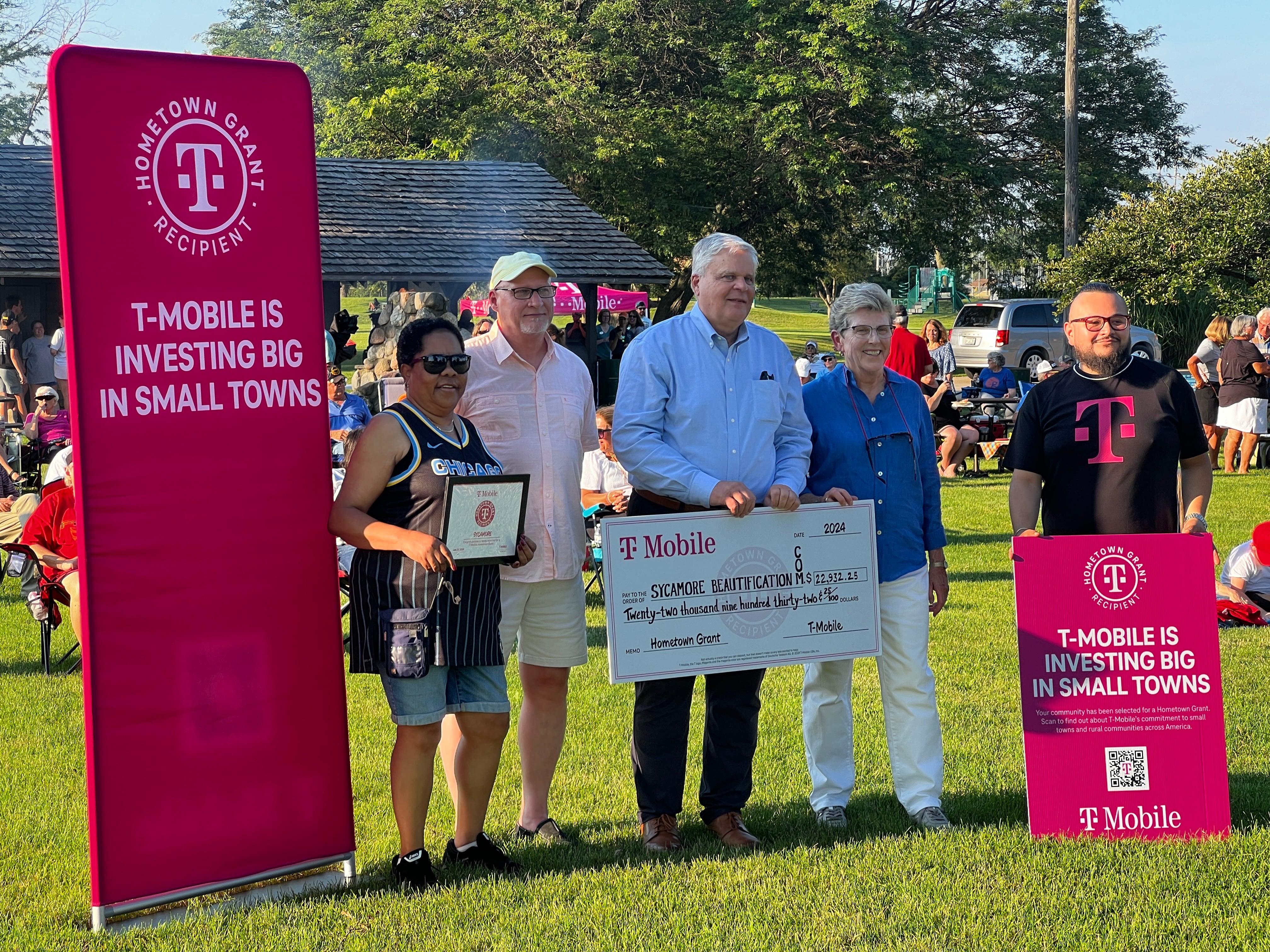 Sycamore beautification committee members Cindy Henderson, Mark Zientek, Sycamore Mayor Steve Braser, 1st Ward Alderwoman Alicia Cosky and DeKalb T-Mobil retail store manager Jose Zarate stand together at a July 11, 2024 Sycamore Music in the Park event, after Zarate presented the city with a check for nearly $23,000.