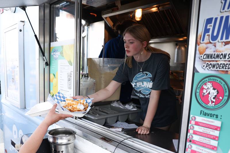 A worker hands out an order of funnel cake at the My Funnel truck at the World of Food Trucks on Saturday, May 18, 2024 at Renwick Community Park in Plainfield