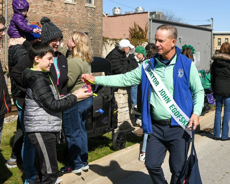 Lemont Mayor John Egofske hands out candy to Conor Marren, 11, of Westmont during the St. Patrick’s parade on March 9, 2024, in downtown Lemont.