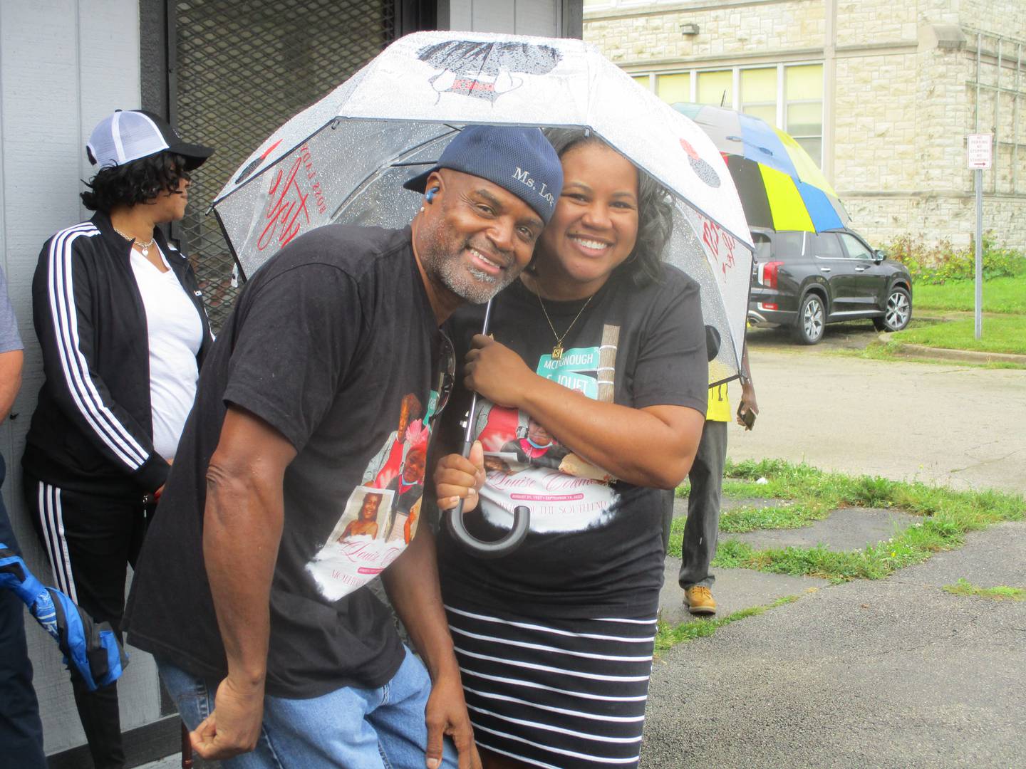 Ricky Coleman and daughter Kiara Ford wait out a rain that fell before the start of a ceremony on Saturday to unveil a sign designating a section of Joliet Street in Joliet as Louis Coleman Drive. Aug. 17, 2024