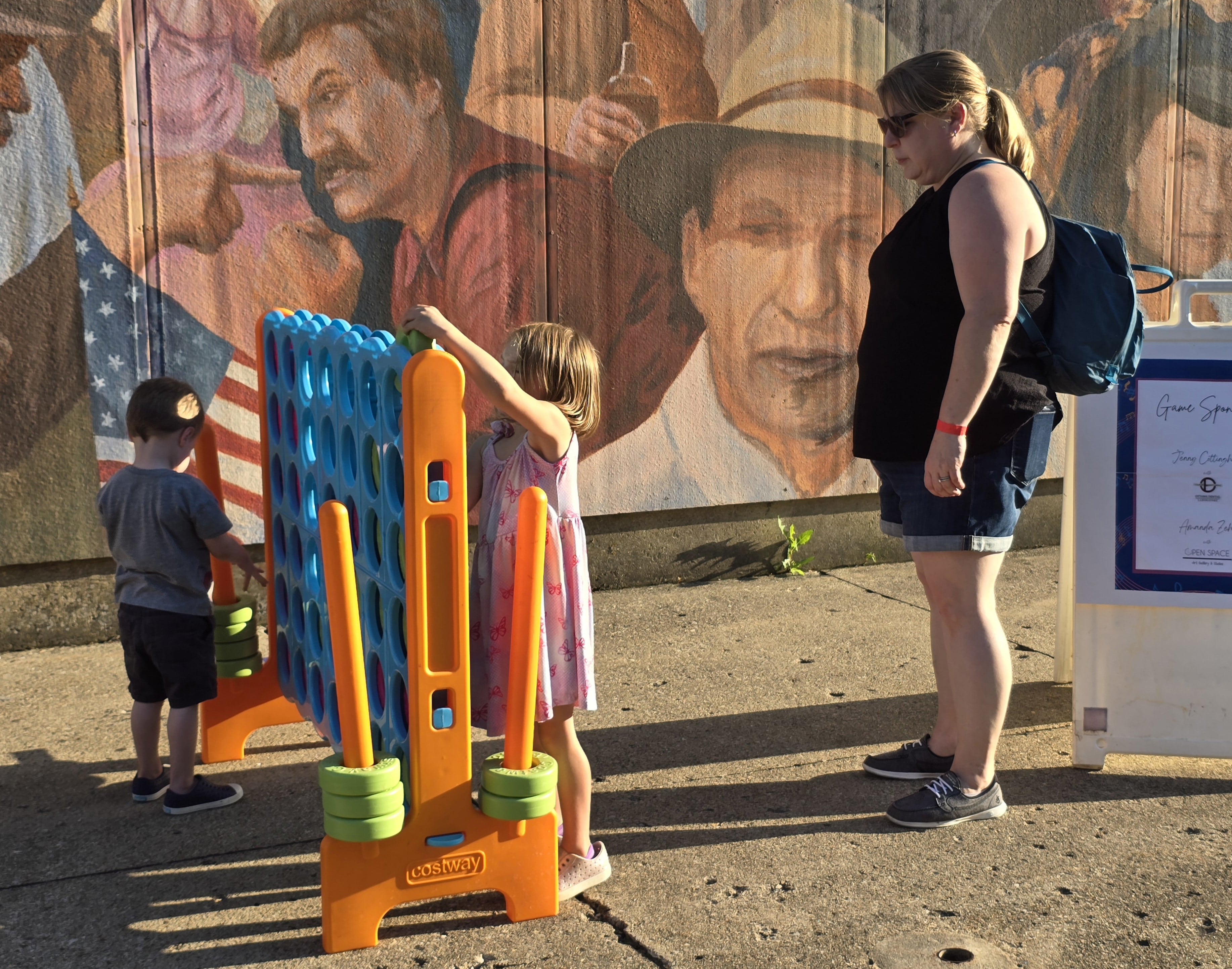 Rebecca Brown watches son Preston and daughter Mia play with the outdoor Connect Four set Wednesday, July 31, 2024, during the Rock the Block event on Jackson Street in Ottawa.