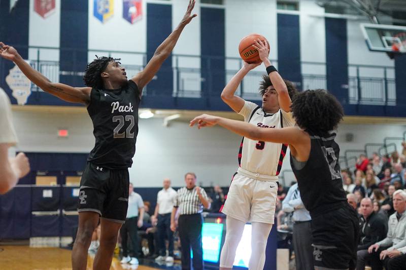 Benet’s Jayden Wright (3) shoots a three pointer against Oswego East's Jehvion Starwood (22) and Drey Wisdom (12) during a Class 4A Oswego East regional final basketball game at Oswego East High School on Friday, Feb 23, 2024.