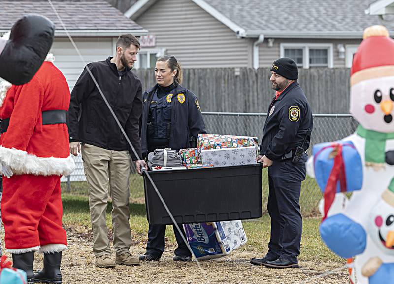 Devin Teske (left) Betony Gluff and Mitch Ottenhausen deliver gifts to the first of six houses Friday, Dec. 22, 2023 in Rock Falls as part of RFPD’s Operation Santa Claus.