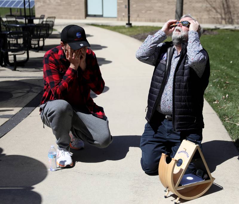 Waubonsee Community College earth science and geology instructor David Voorhees (right) looks at the sun through protective glasses as he sets up a sunspotter device with the help of student Ashton Froehle (left) during the solar eclipse on Monday, April 8, 2024 at the college’s Sugar Grove campus.