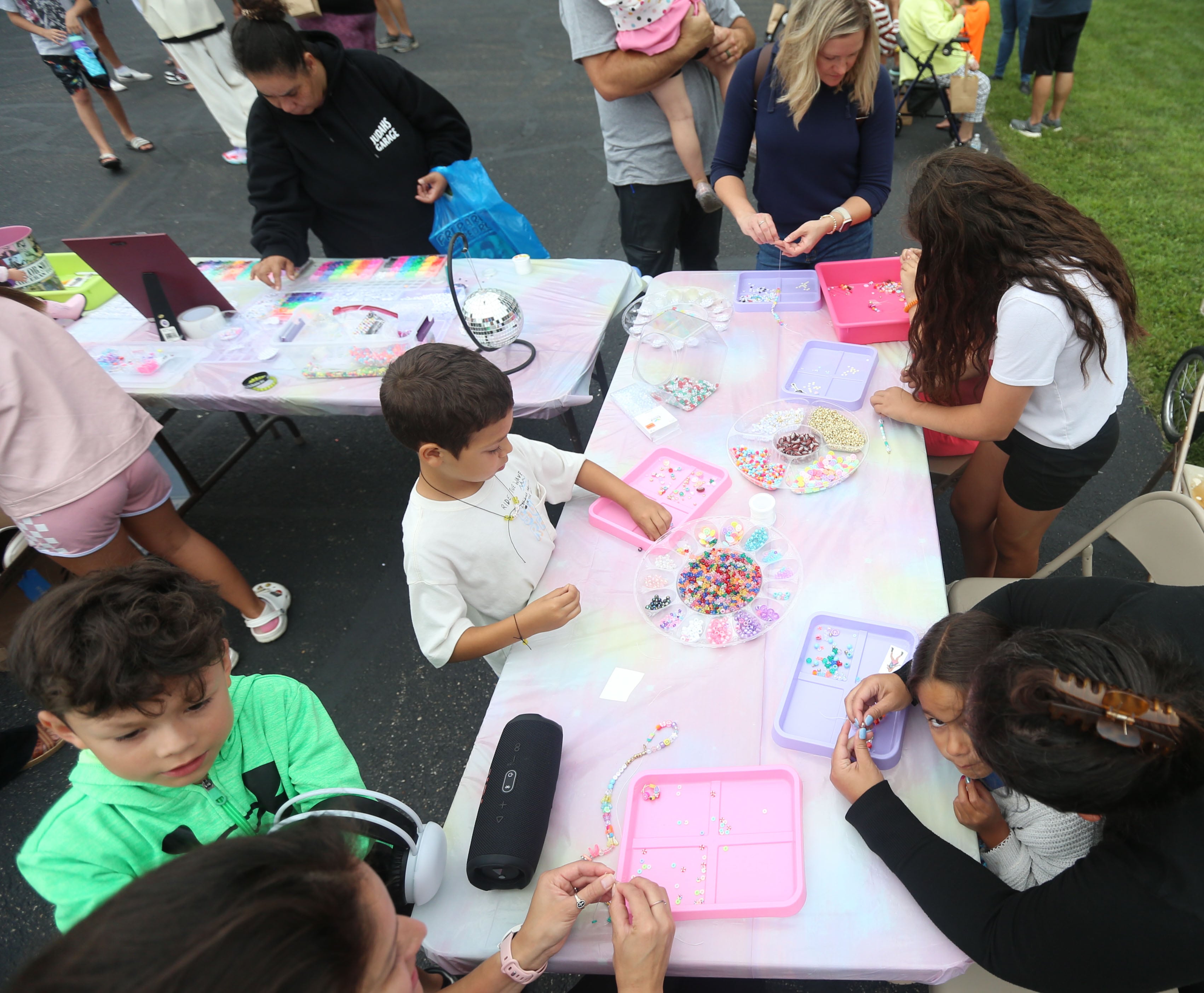 Kids make bracelets in a Taylor Swift themed booth during  the National Night Out event on Tuesday, Aug. 6, 2024 at Kirby Park in Spring Valley.