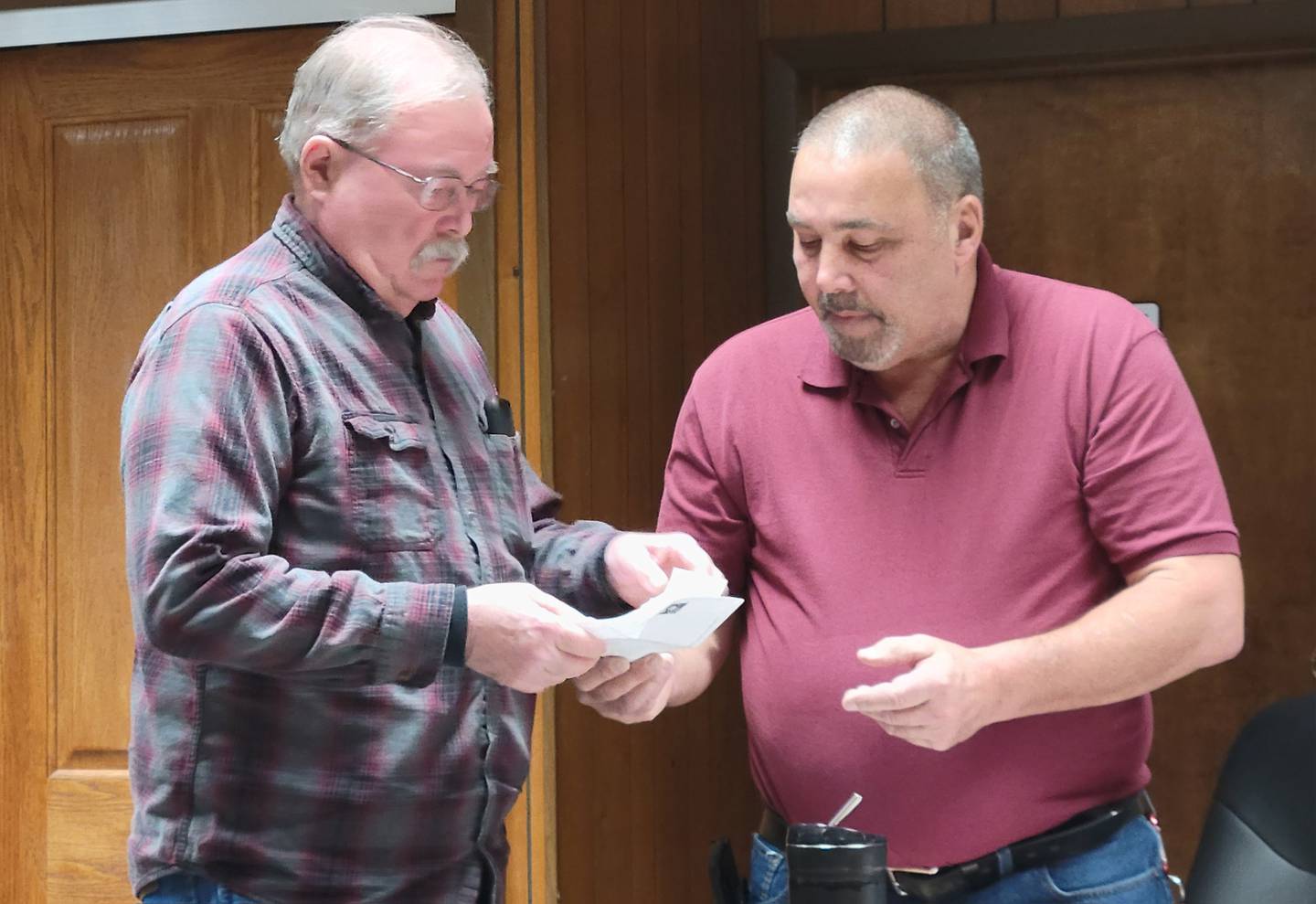 Marseilles Commissioner Jim Buckingham (right) presents a check to Greg Stock of the Middle East Conflicts Memorial Wall board in the name of the late Vickie Finan.