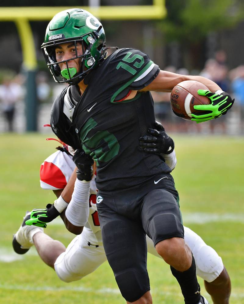 Glenbard West's Mason Ellens (15) sheds a Marist tackler for a big gain during a game on Aug. 26, 2023 at Glenbard West High School in Glen Ellyn.