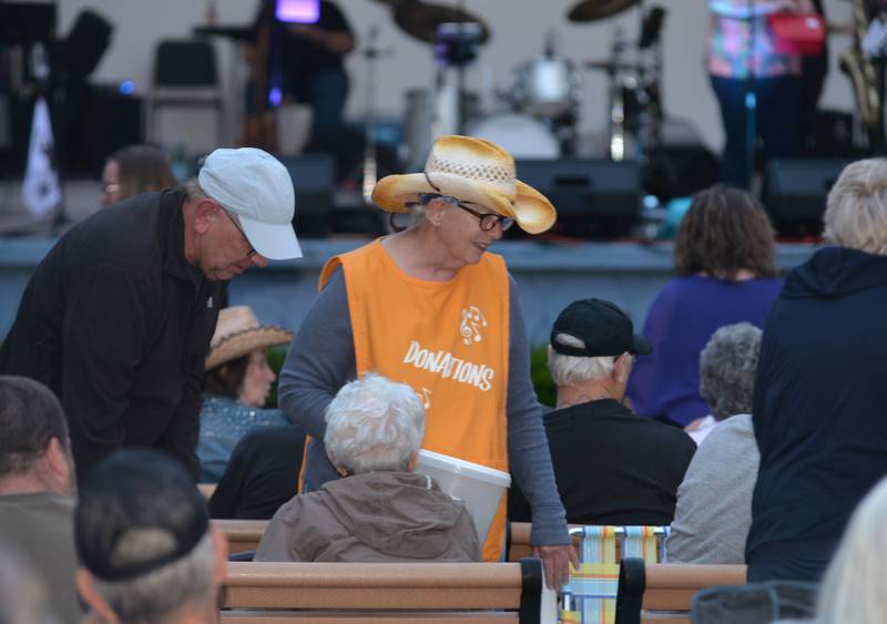 A volunteer seeks donations from the crowd during a break in the music at the opening night of the Jamboree music series in downtown Mt. Morris on Friday, June 7, 2024. The free concert series continues through the summer each Friday night on the campus.