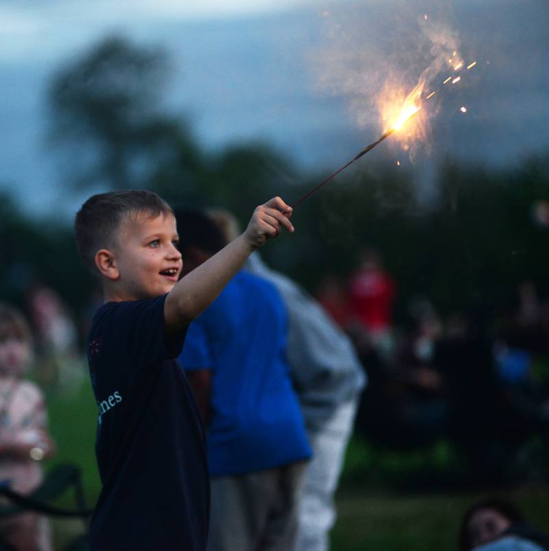 Owen Russell, 7, of Florida, plays with a sparkler as he waits for the fireworks to begin at Let Freedom Ring in Mt. Morris on Thursday, July 4, 2024.