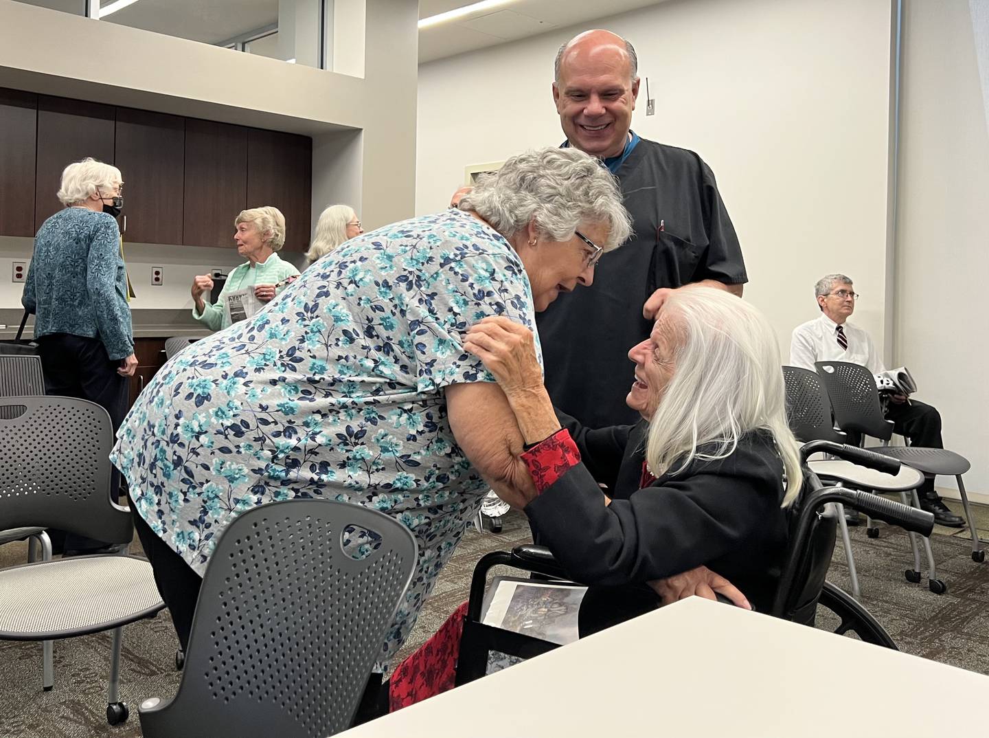 Thirty-three-year DeKalb County Rehab and Nursing Center employee, Chuck Simpson, 53, the president of American Federation of State, County and Municipal Employees No. 3537, watches as his mother, Carolyn Simpson, 74, hugs Mary Roman on July 11, 2023. Roman, 88, has been a resident of the county-owned nursing home for the past eight years, and is staunchly against the sale of the facility.