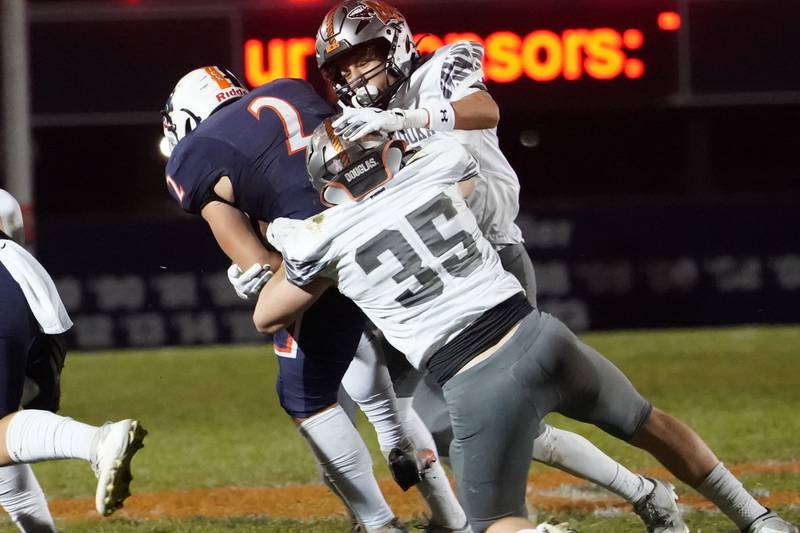 Minooka's Nathan Gonzalez (3) and William Mutz (35) tackle Oswego’s Lucas Andersen (2) during a football game at Oswego High School on Friday, October 18, 2024.