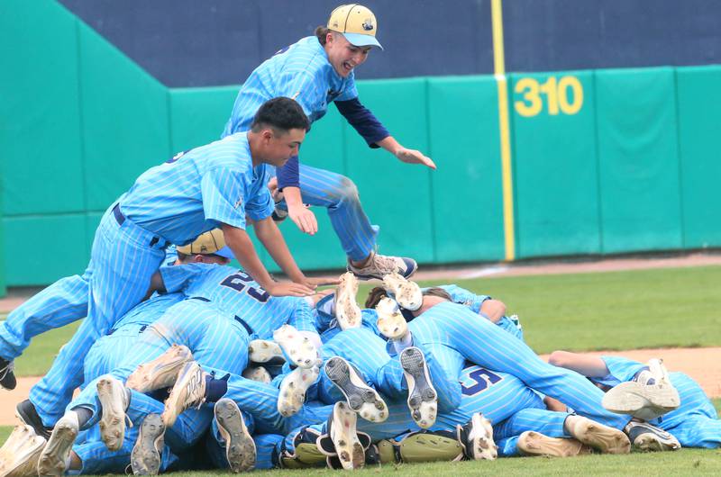 Marquette players David Clairmont and Carson Zellers leap on top of a pile of their teammates after defeating Altamont to win the Class 1A State championship title on Saturday, June 1, 2024 at Dozer Park in Peoria.