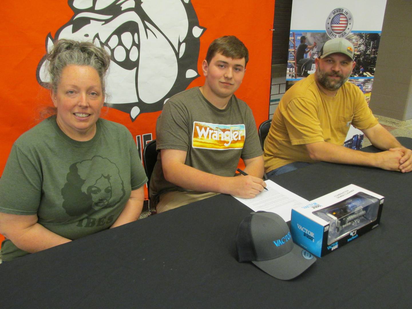 Streator High School student Hayden Wolfe accepts a full-time position at Vactor Manufacturing during a signing day event Thursday, May 11, 2023. He is with his parents Nikki Rambo and Eric Wolfe.