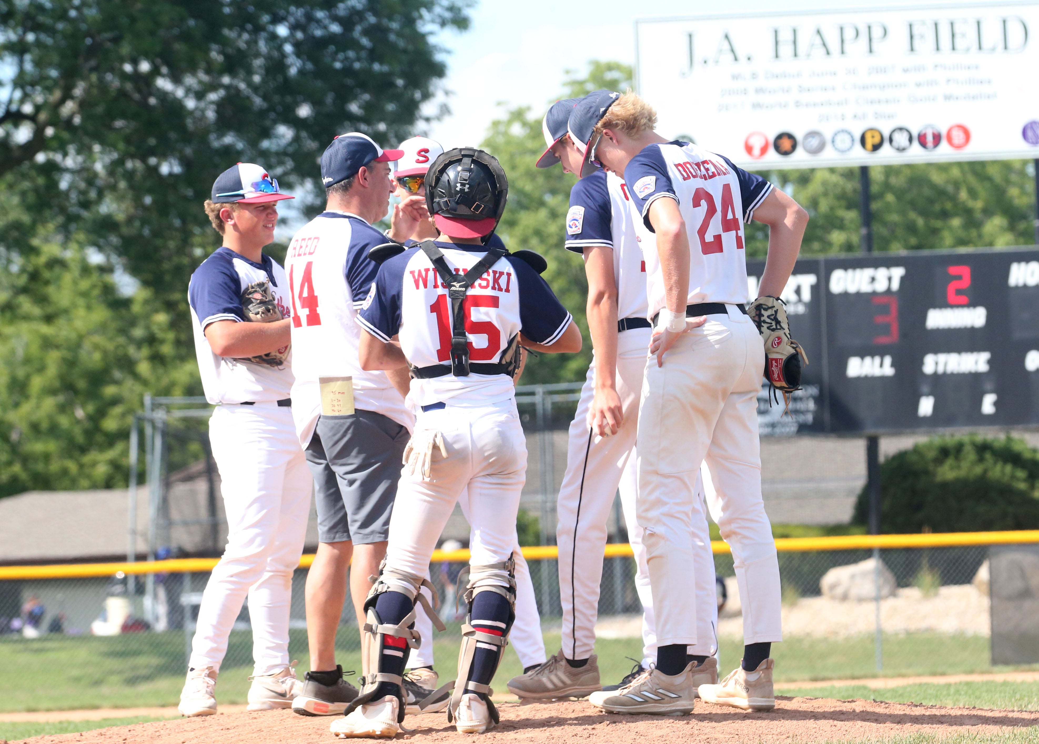 Members of the Michigan Senior League baseball team gather on the mound while playing Burbank during the Central Regional  Baseball Tournament championship game on Thursday, July 18, 2024 at J.A. Happ Field in Washington Park in Peru.