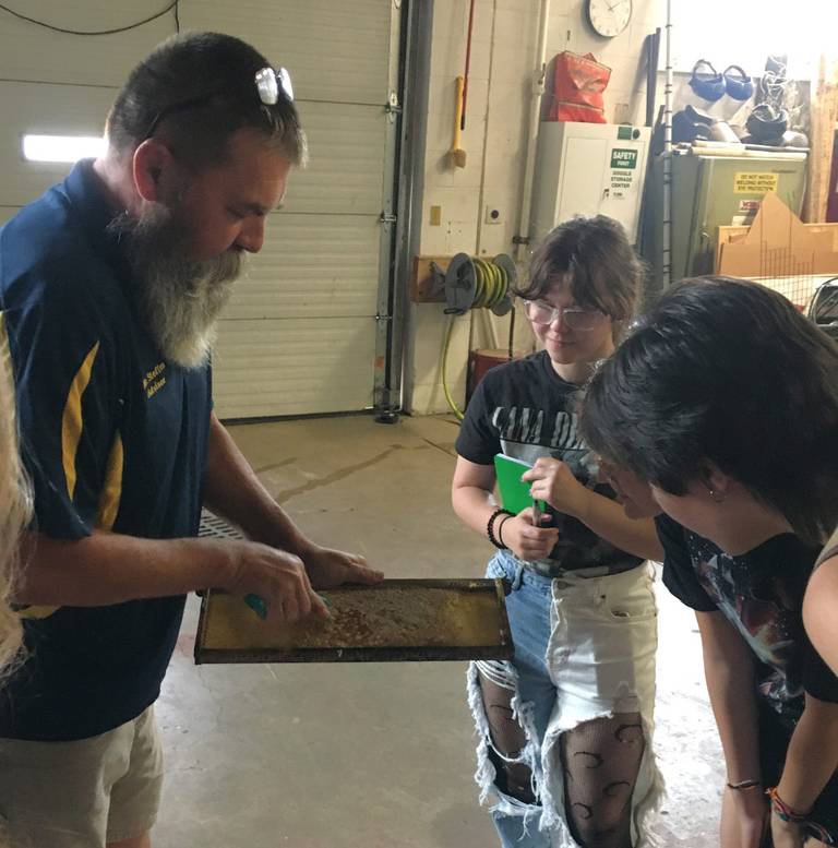 Joe Steffen, left, agriculture teacher at Newark High School, shares their school made honey on the comb with Kendall County students.