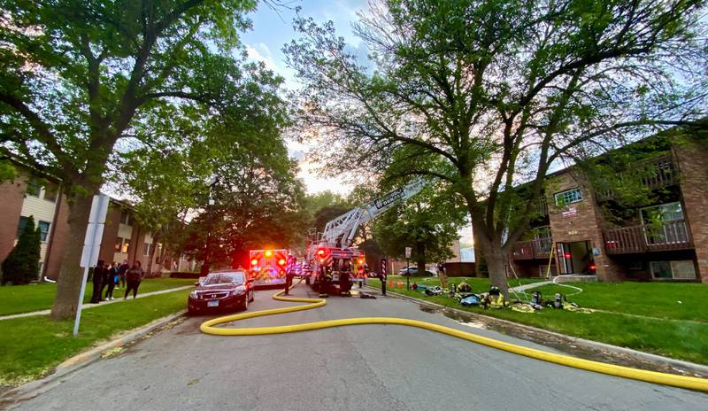 Neighbors and residents gather outside a corner at Kimberly Drive and Normal Road in front of a building while crews work to battle a structure fire at a Husky Ridge apartment complex in the 800 block of Kimberly Drive, DeKalb, on Wednesday evening, May 29, 2024.