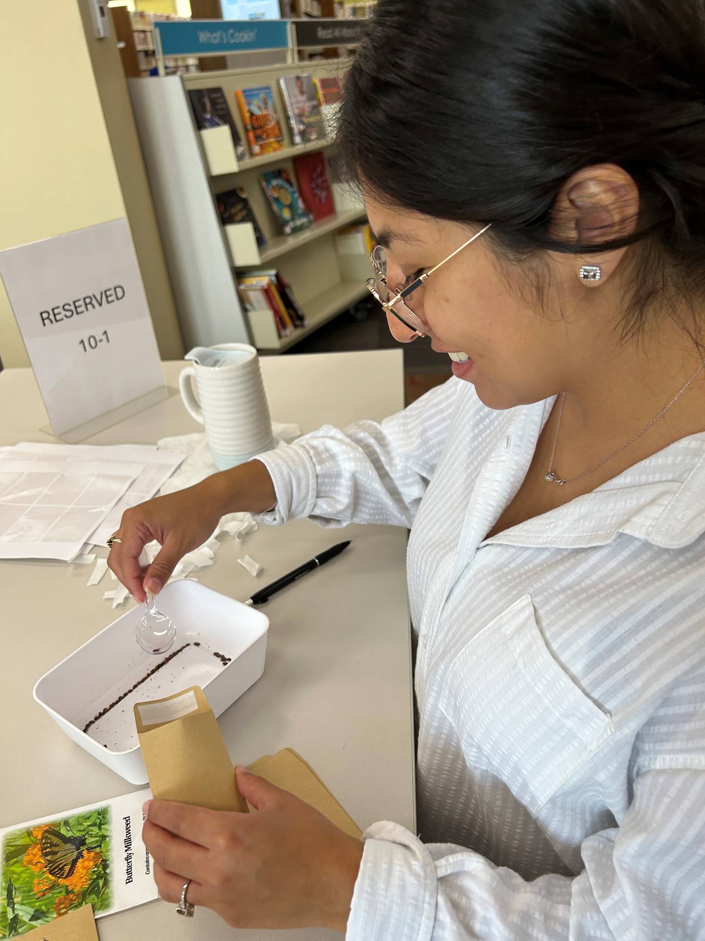 Crystal Lake Public Library technical assistant Mariana Molina fills seed packets for the new seed library.