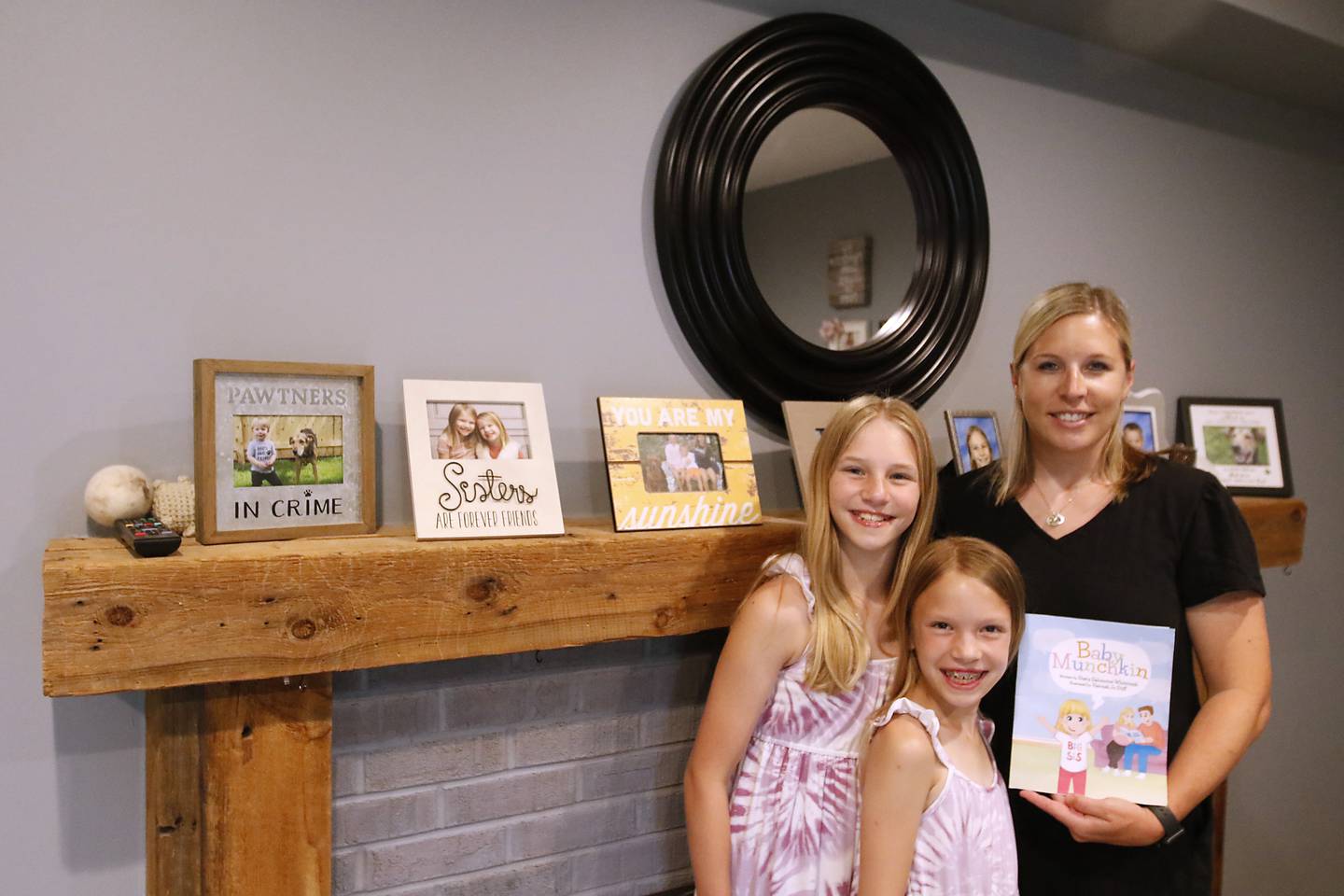 Stacy Salomone Whitcomb holds her new children’s book, “Baby Munchkin” next to her children, Reese, 9, (center) and Hayden, 11, (right) whom the book is based, at their hame in Cary on Friday, June 28, 2024.