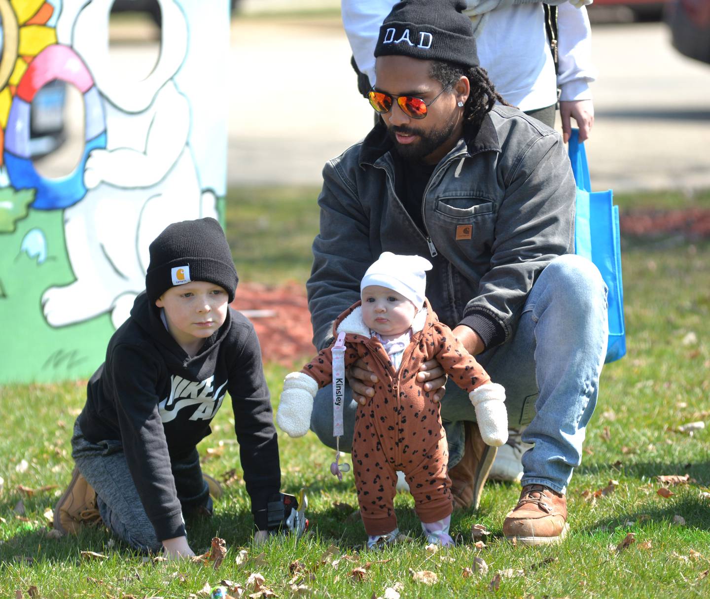 Shaquille Campbell, of Freeport, holds his daughter Kinsley, three months, as Nolan Newhausen, 6, watches at the Forreston Lions and FABA's Easter egg hunt and luncheon at Memorial Park in Forreston on Saturday, March 30, 2024.