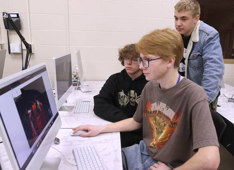 Johnny Howard, (left) a junior, Owen Foster, a junior, and Lane Schumacher, (right) a senior, at one of the computers Thursday, March 7, 2024, at DeKalb High School. The students are part of the BarbCast network that broadcasts live streaming video of sports and events at the school as well as putting together promotional materials.