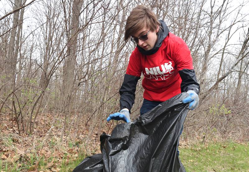 Northern Illinois University sophomore Joseph Richards, from Crete, a member of NIU Cares, bags up garbage he collected Friday, April 29, 2022, on campus near the West Lagoon. NIU Cares, with the help of the Trash Squirrels, was hosting a community cleanup event, going to several locations in DeKalb to pick up litter.