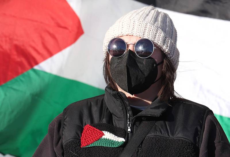 A protester stands in front of a Palestinian flag during a rally against the Israel–Hamas war Thursday, Feb. 29, 2024, outside the Holmes Student Center at Northern Illinois University in DeKalb.