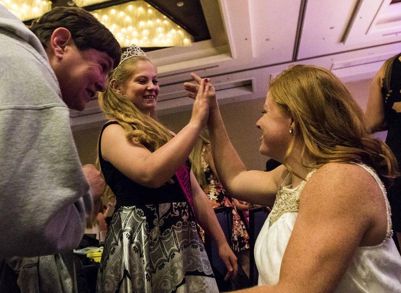 Miss Amazing Teen Illinois Edith Reynolds (center), 19, of DeKalb, gets a high-five from Paralympic athlete Mary Kate Callahan as Reynolds and her mother, Mary Reynolds, talk with Callahan after Callahan's speech during the National Miss Amazing Gala on June 30, 2016, at the Hyatt Regency O'Hare ballroom in Rosemont during the opening night of the competition.