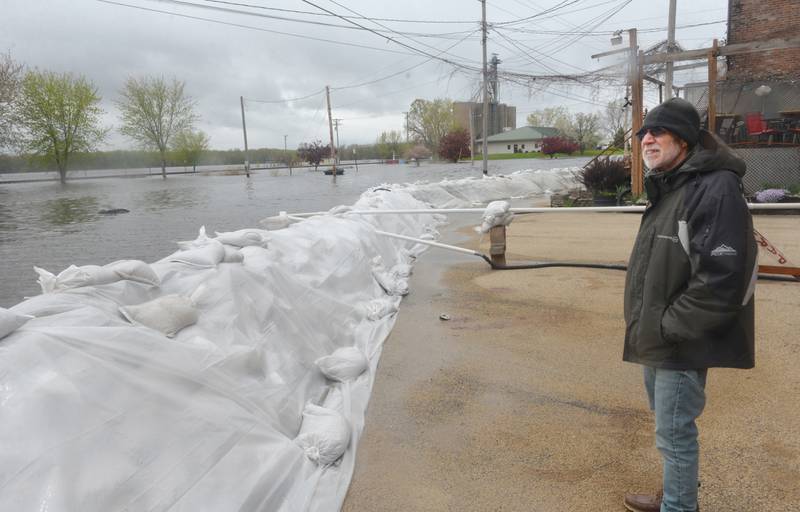 Stan Kosmecki of Mt. Carroll watches the Mississippi River as it rose Sunday flooding streets just west of Main Street in downtown Savanna. Officials along with volunteers and inmates from the Kewanee and East Moline, constructed a sandbag wall in anticipation of the river levels rising past the 21-foot mark. The wall was holding the water away from Main Street as of Sunday afternoon. The two trees on the left indicate where the river's bank is normally.