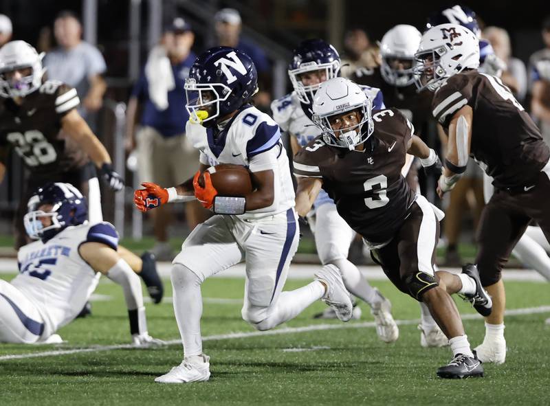 Nazareth's Edward McClain Jr. (0) tries to outrun Mt. Carmel's Le'Javier Payne (3) during the varsity football game between Nazareth Academy and Mt. Carmel high school on Friday, Sep. 13, 2024 in Chicago.