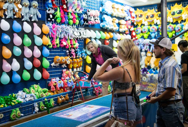 Lilie Whelan, left, and Kyle Zitkus of Elburn play a carnival game at the Kane County Fair in St. Charles on Saturday, July 15, 2023.