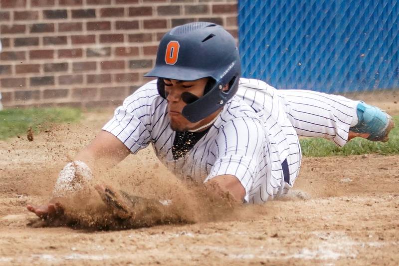 Oswego’s Gabriel Herrera (8) beats the throw to home to score a run against Oswego East during a baseball game at Oswego High School on Monday, May 13, 2024.