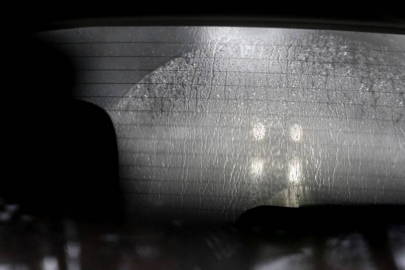 The headlights of car are seen through the rear window of a car on Walkup Avenue in Crystal Lake on Tuesday, Jan. 23, 2023. Residents throughout northern Illinois woke up to icy and slippery roads.