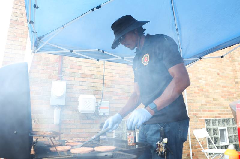 DJ Green, a Joliet Police Detective and Vice President of the Joliet Black Police Association, works a new batch of burgers at the Healing the Hood event held at the St. Mark CME Church in Joliet on Saturday June 29, 2024.