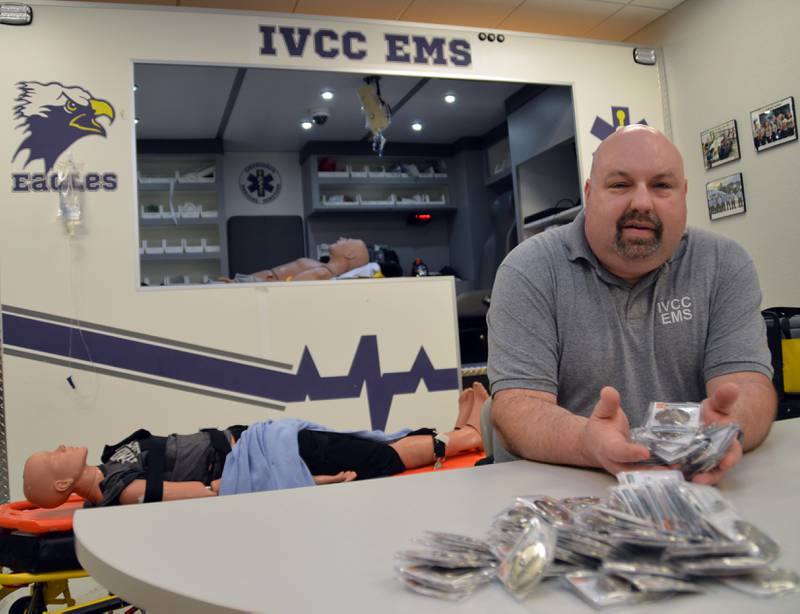 When Illinois Valley Community College Emergency Medical Services graduates passed their final exam this spring, Program Coordinator Nick Fish passed out brass Challenge Coins as tokens of achievement and fellowship. But Fish (shown here with the coins in IVCC’s simulation lab) hopes the coins also present a lifeline to cope with a challenging profession.