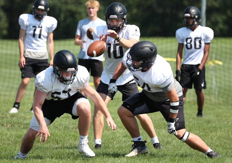 Sycamore offensive linemen move in front of quarterback Burke Gautcher as the ball is snapped Monday, July 15, 2024, during summer football camp at Sycamore High School.