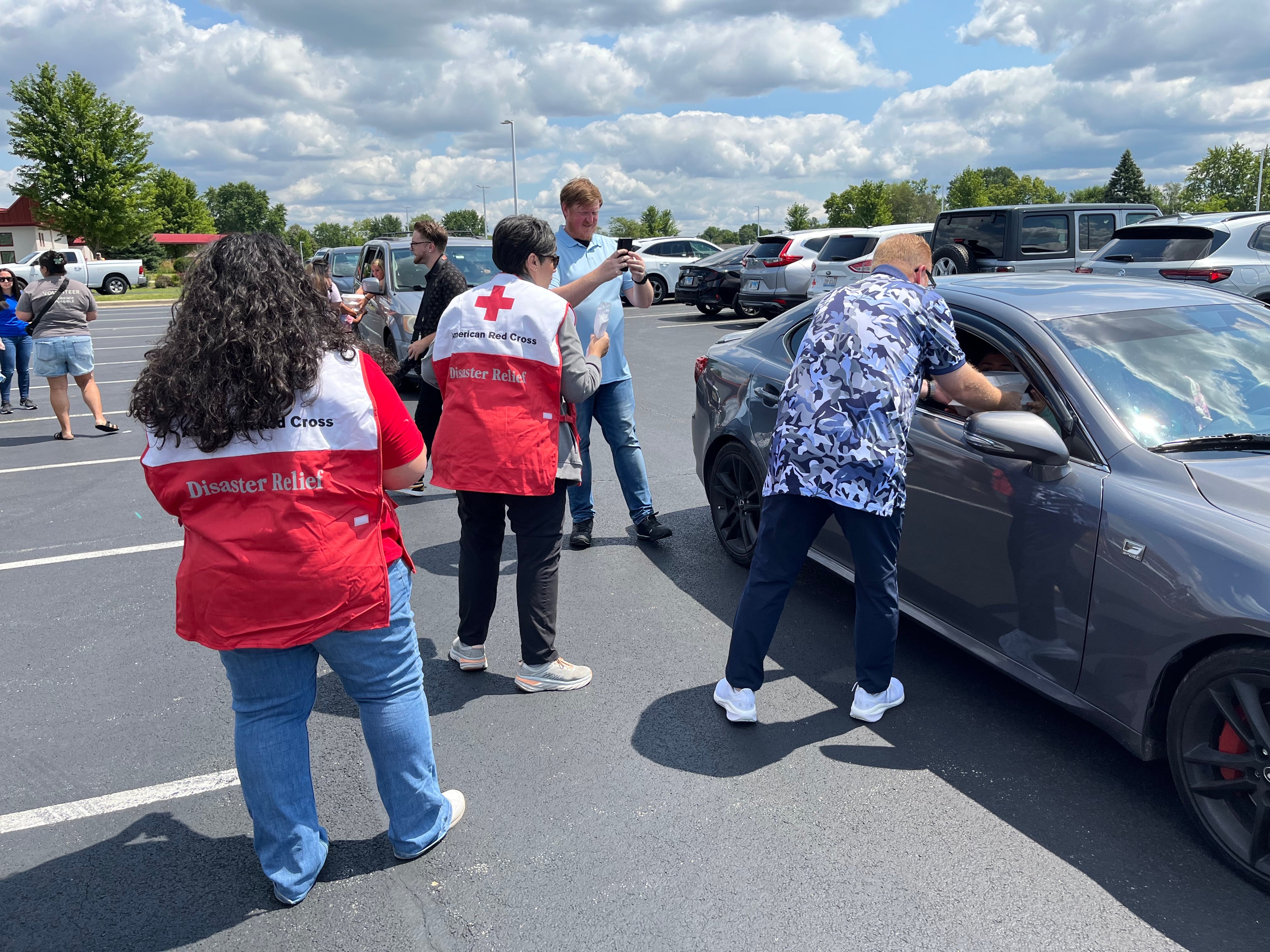 Rusty Railey, lead pastor of Victory City Church (right), hands meals to visitors on Thursday, July 18, 2024, at the church parking lot in Joliet. The church partnered with Joliet city officials and American Red Cross to help residents who've been affected by the storms on Monday, July 15, 2024.