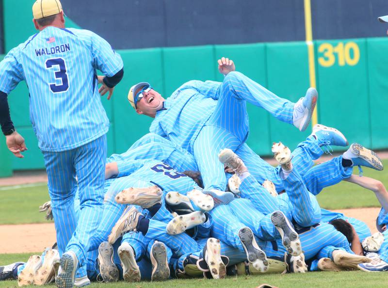 Marquette assistant coach Brian Bressner leaps on top of a pile of his players after defeating Altamont to win the Class 1A State championship title on Saturday, June 1, 2024 at Dozer Park in Peoria.