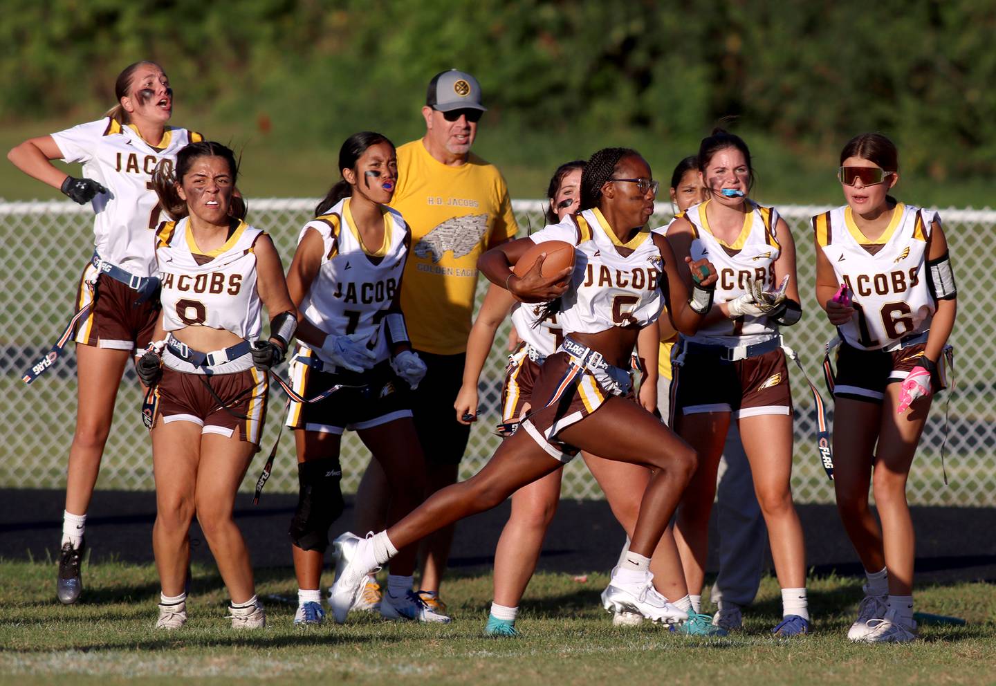 Jacobs’ players shout encouragement as Aaliyah Guichon hustles toward the end zone with a touchdown in varsity flag football on Tuesday, Sept. 3, 2024, at Dundee-Crown High School in Carpentersville.