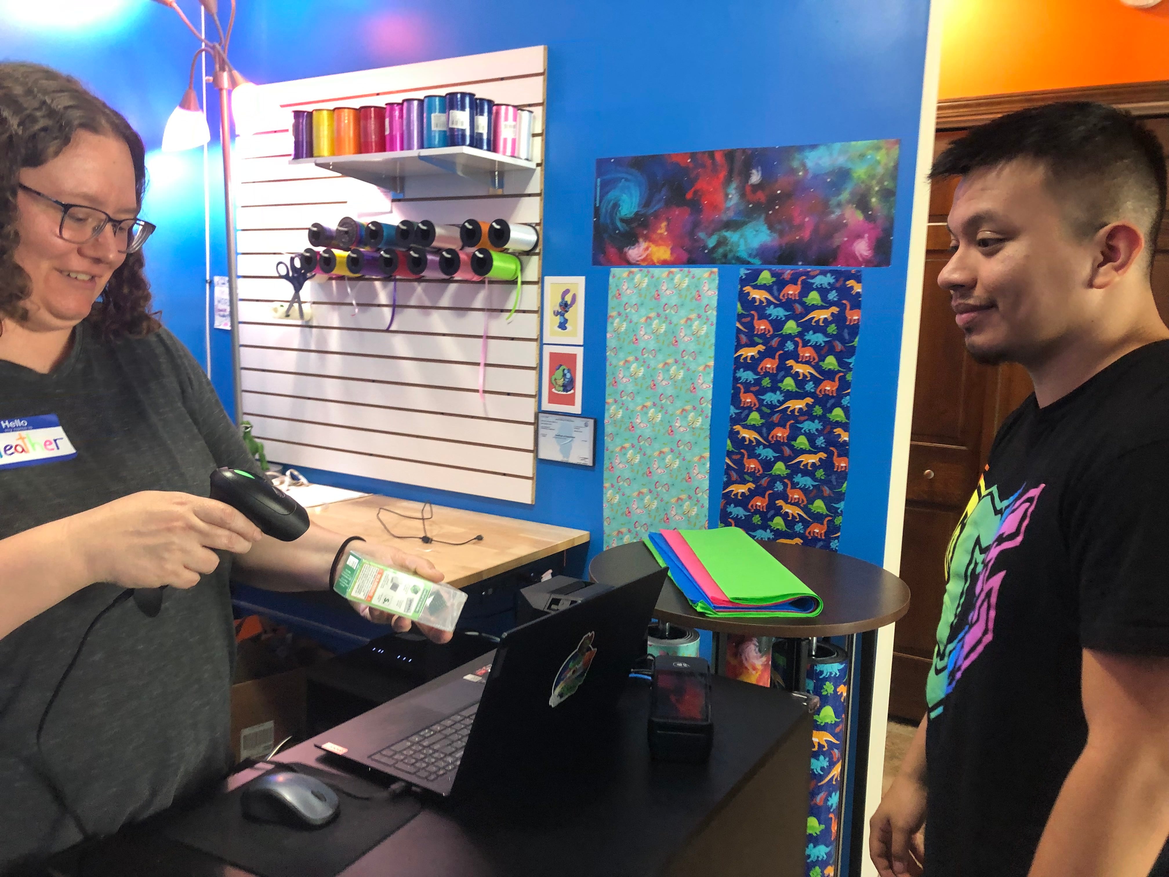 Heather Weatherwax scans a speks toy for customer Alexis Zepeda at Revelry Toys in Woodstock Aug. 17, 2024.