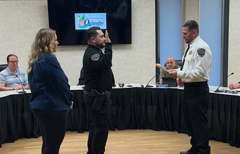 Oglesby Police Chief Mike Margis (right) swears in new officer Dakotah Baker while wife Megan (left) looks on Monday, Oct. 21, 2024, at the Oglesby City Council meeting.