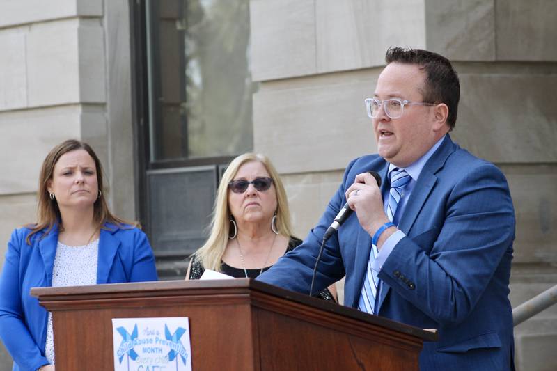 Matthew T. Klahn, associate judge for Lee County in the 15th Circuit, addresses the crowd of about 50 people who are participating in the Hands Around the Courthouse event Friday, April 14, 2023 to observe National Child Abuse Prevention Month. From left stand Jessica Cash, executive director at Shining Star Children's Advocacy Center, and child abuse prevention advocate Karen Digby.