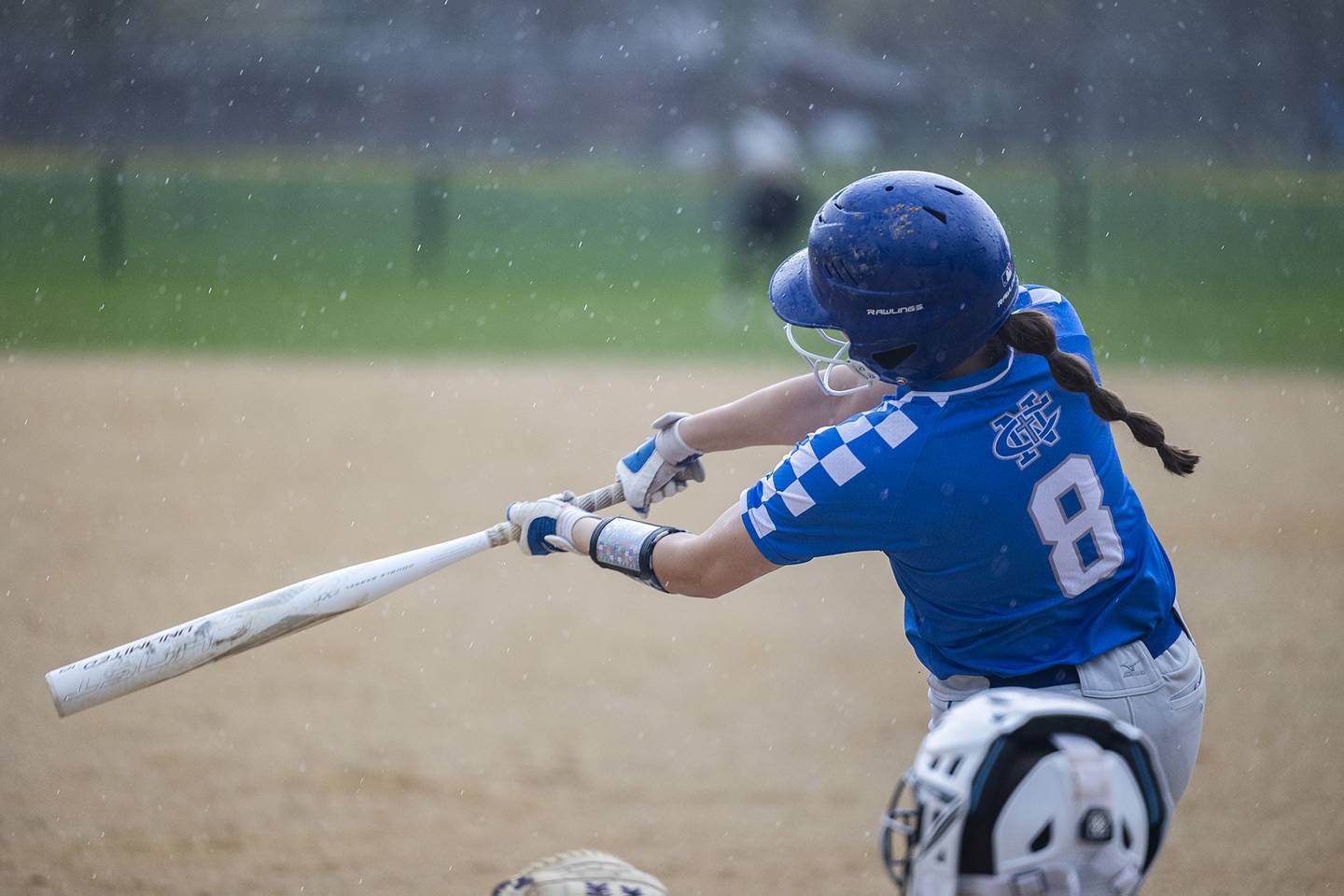 Newman’s Lucy Oetting drives connects for a hit as the rain starts to fall against Dixon Thursday, April 11, 2024 at Reynolds Field in Dixon.