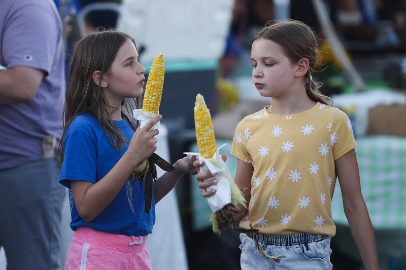 Aubrey Stevenson and her sister Devi enjoy corn on the cob at the Taste of Joliet on Friday, June 21, 2024 at Joliet Memorial Stadium.