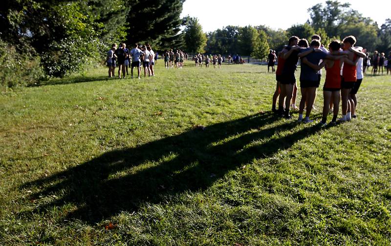 Teams huddle before the boys race of the McHenry County Cross Country Invite on Saturday, August 31, 2024, at McHenry Township Park in Johnsburg.