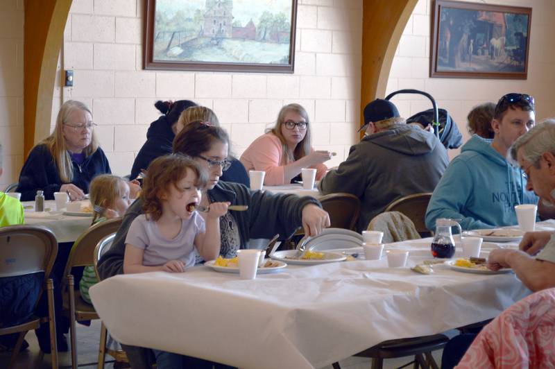 Riley Lawson, 3, takes a big bite of breakfast while sitting on the lap of Tiffany Lawson, of Dixon, during the Leaf River Lions Club's Breakfast with Bunny on April 8, 2023, in the Bertolet Building. An Easter egg hunt following the breakfast.