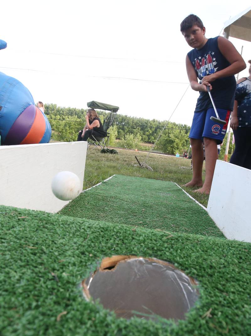 Godina Jeremiah of Peru, practices mini putting in the kids zone before the fireworks on Wednesday, July 3, 2024 along Water Street in Peru.