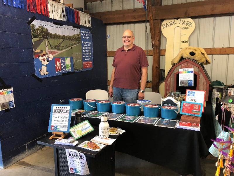 Morrison Mayor Scott Vandermyde  Thursday at the On the Move with Parks and Rec booth at this week's Whiteside County Fair in Morrison. At the booth, which is open until 7 tonight and until 4 p.m. Saturday, people can vote with donations for their favorite dog picture, and also sign up for a raffle for a fire pit. Also at the booth are dog houses built by Jim Strating that will be sold in a silent auction at the Dog Days of Summer Pooch Picnic, being held from 11 a.m. to 3 p.m. Sept. 18, after the annual Harvest Hammer 5k in Morrison. Money raised is being used to build a dog park.