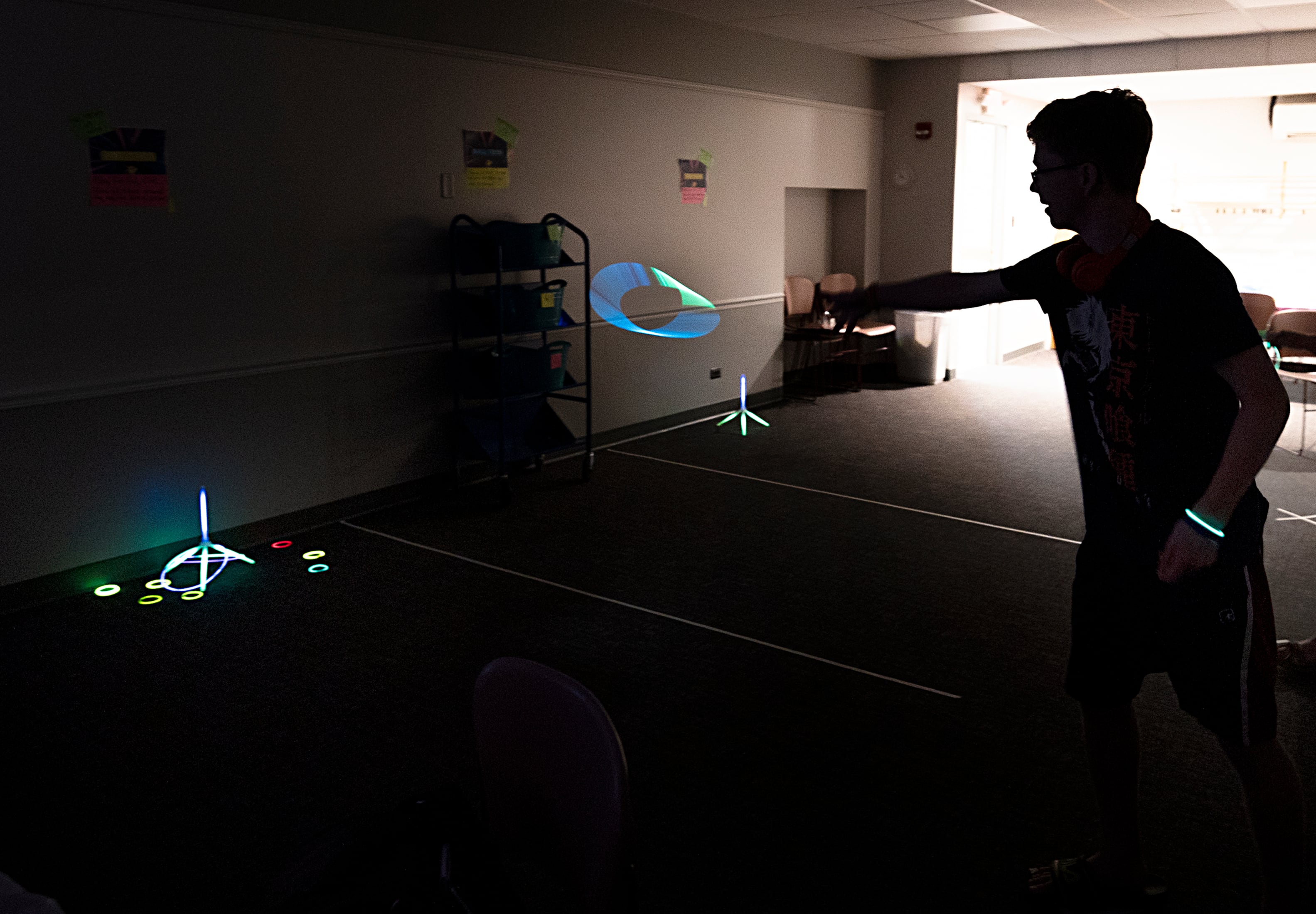 The lights were turned off Tuesday, July 16, 2024, at the Dixon Public Library to enhance the look of its young adult glow party. Here, Josh Coss, 17, throws a ring at a target as part of the fun. About once a quarter moving forward, the library will host a teen-based program.