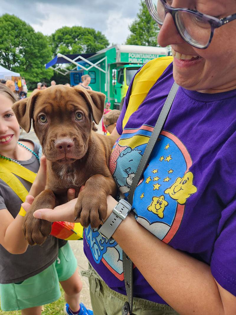 Allaina Humphreys, chairperson of Bolingbrook Pride, takes a break with a puppy snuggle during the 2023 Pride Picnic.